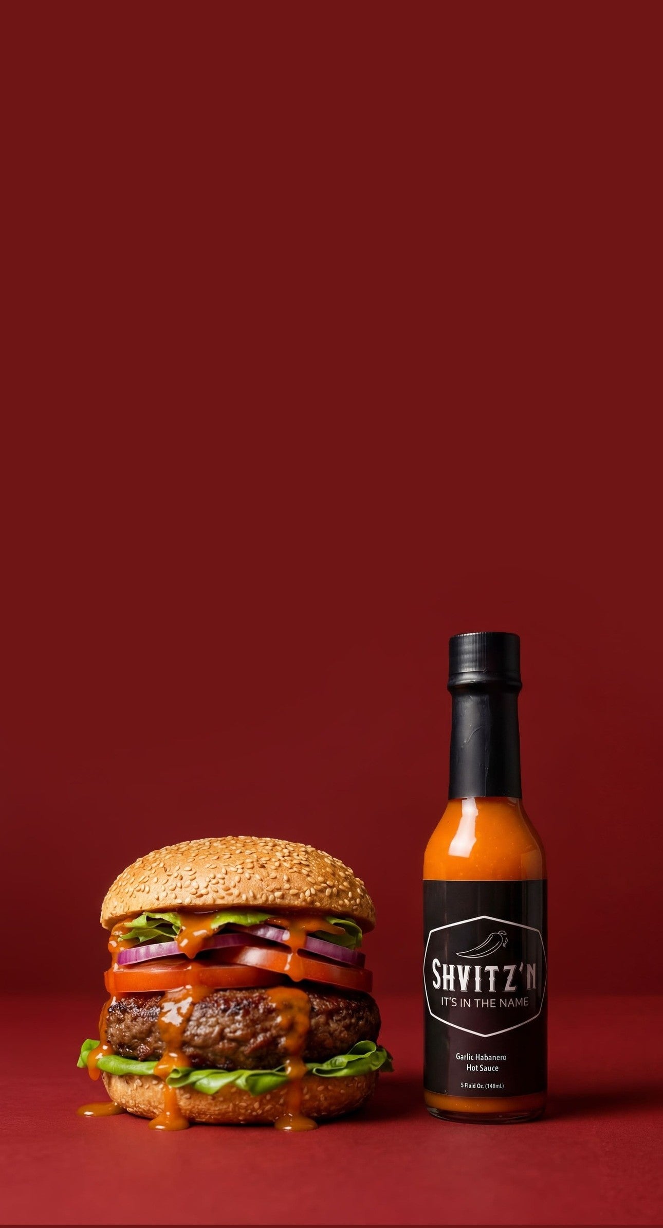 Shvitzn Garlic Habanero Hot Sauce Bottle with a juicy burger. Bold, OU-certified kosher flavor that goes on everything!